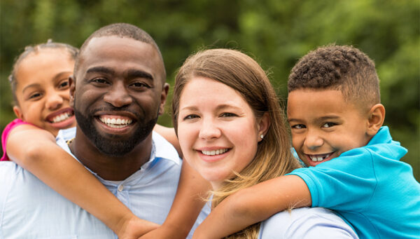 Lachend gezin met twee kinderen op de rug bij ouders