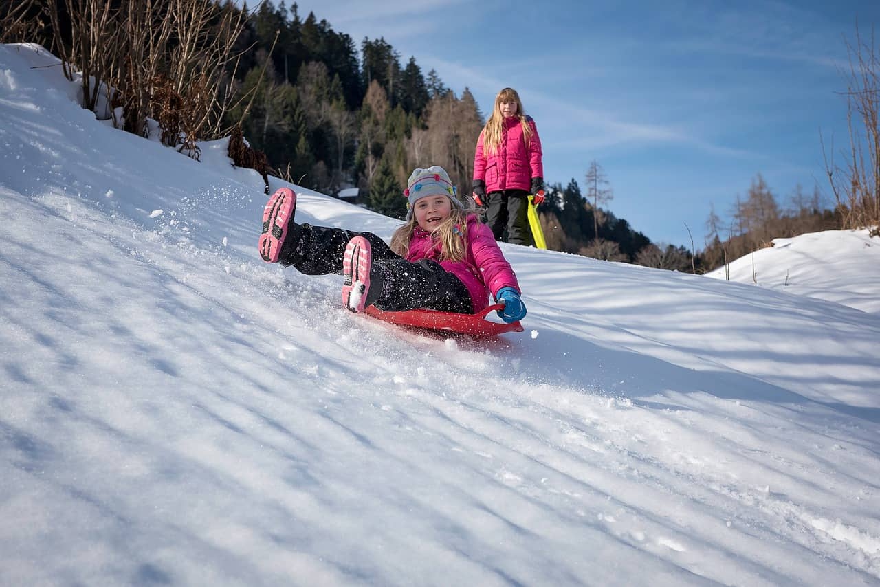 Meisje op slee in de sneeuw glijdt een heuvel af
