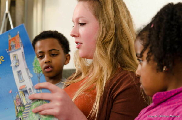 Jonge vrouw leest twee kinderen voor uit kinderboek