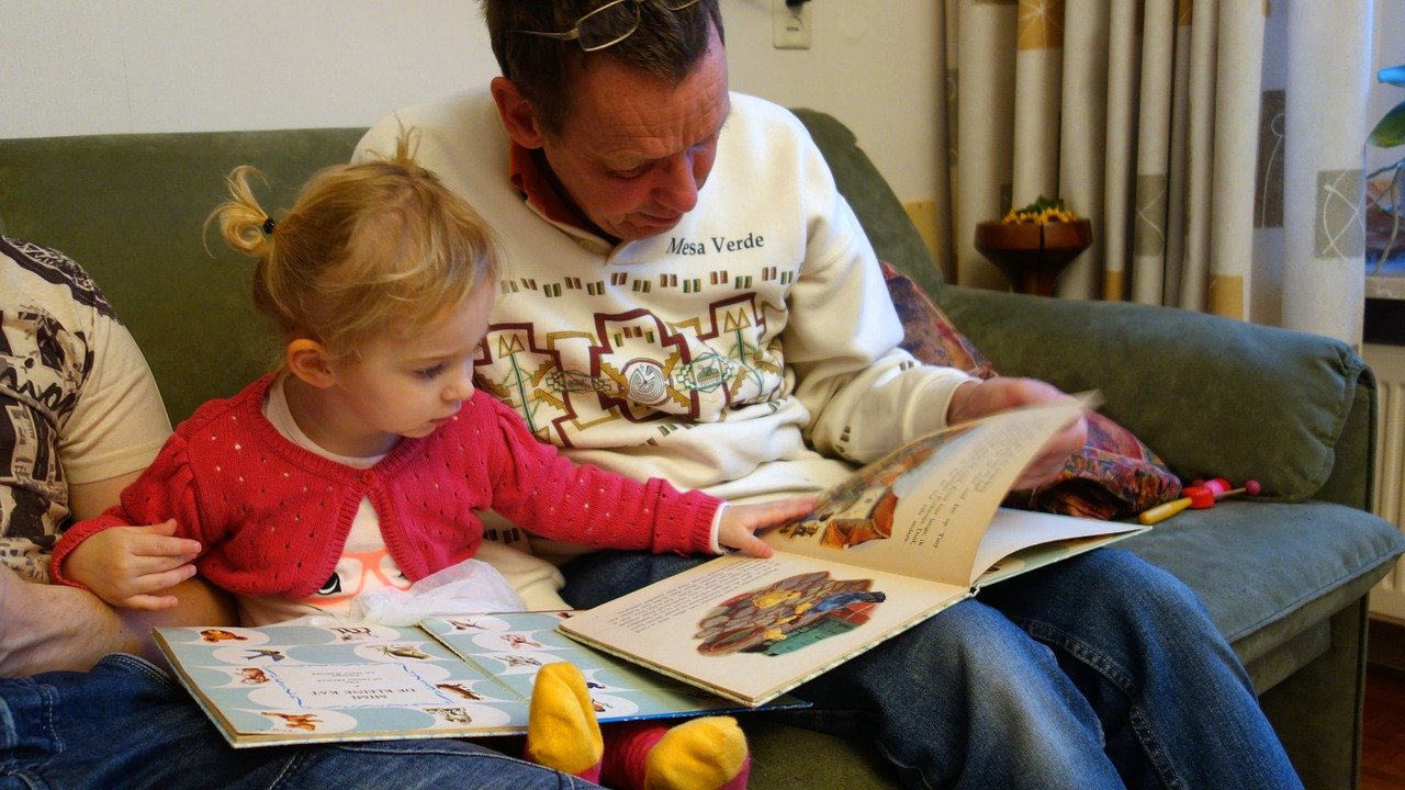 Opa leest voor aan kleindochter op de bank