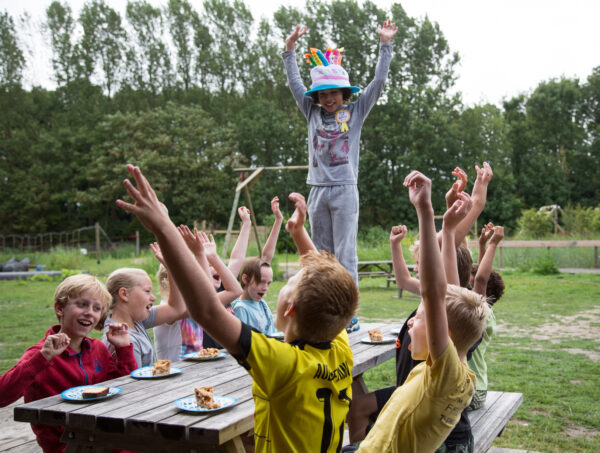 Kinderen buiten aan een houten tafel die een verjaardag vieren