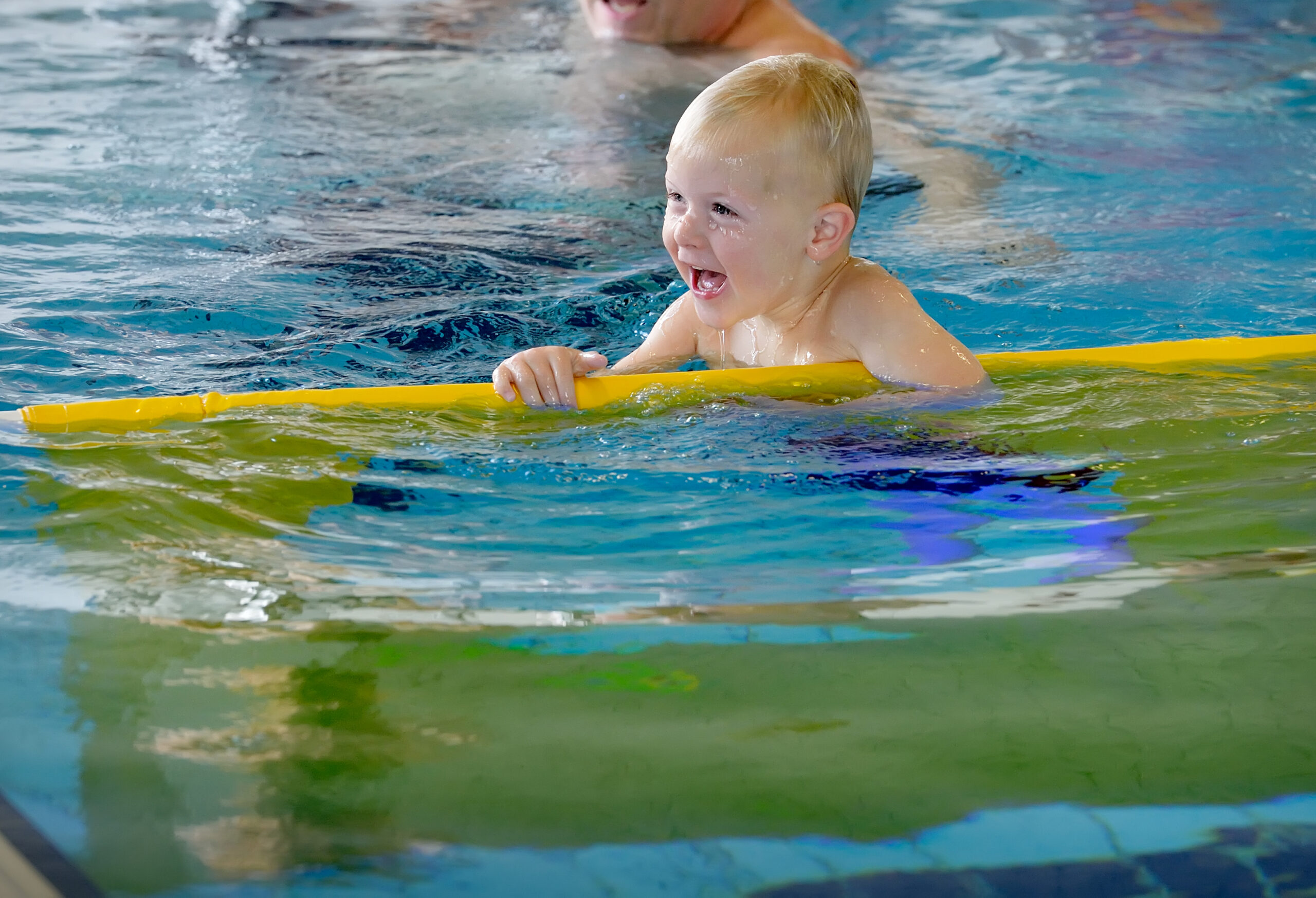 Zwemmend kind in zwembad met geel kunststof zwemattribuut/hulpmiddel