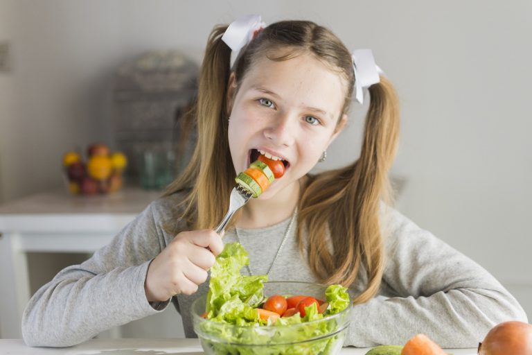 Foto van kind dat een gezonde salade eet