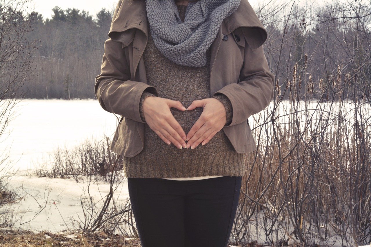 zwangere vrouw vouwt haar handen tot een hartje