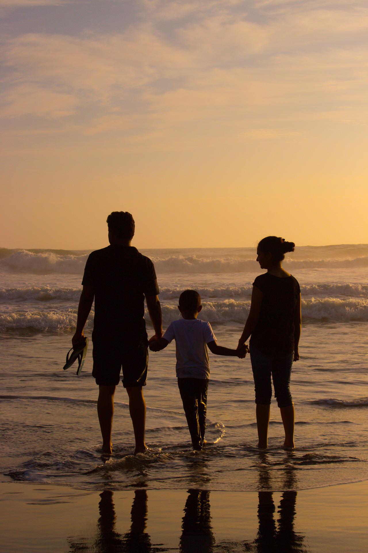 ouders en kind tijdens zonsondergang op strand