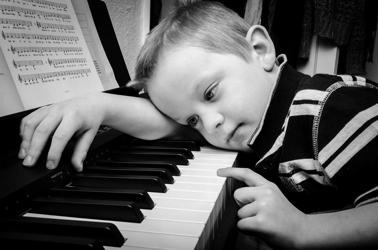jongen ligt met hoofd op piano