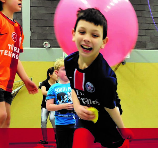 Kinderen spelend met grote ballonnen in een sporthal.