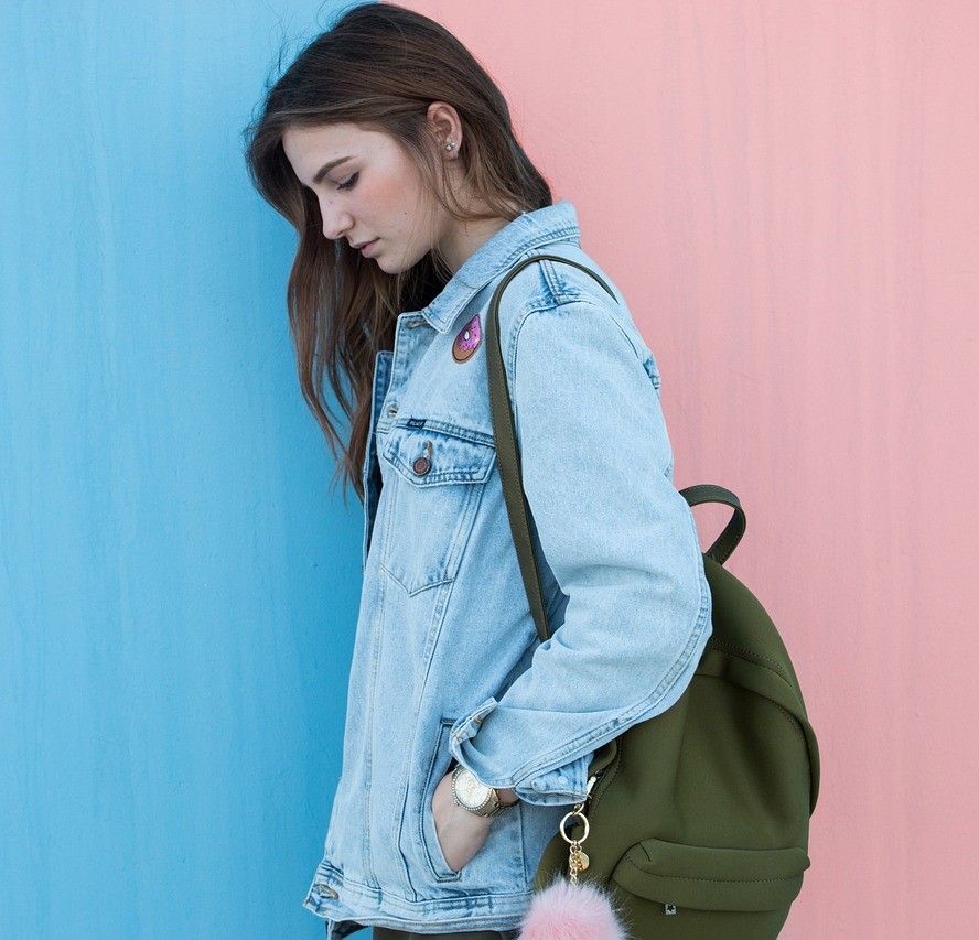 Sombere jongere (meisje) tegen roze-blauwe muur