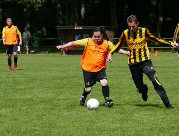 Voetballende mensen op grasveld tijdens sporten voor mensen met een beperking