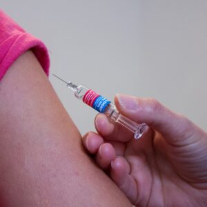 hand met injectiespuit en arm van degene die gevaccineerd wordt