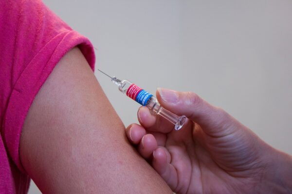 hand met injectiespuit en arm van degene die gevaccineerd wordt