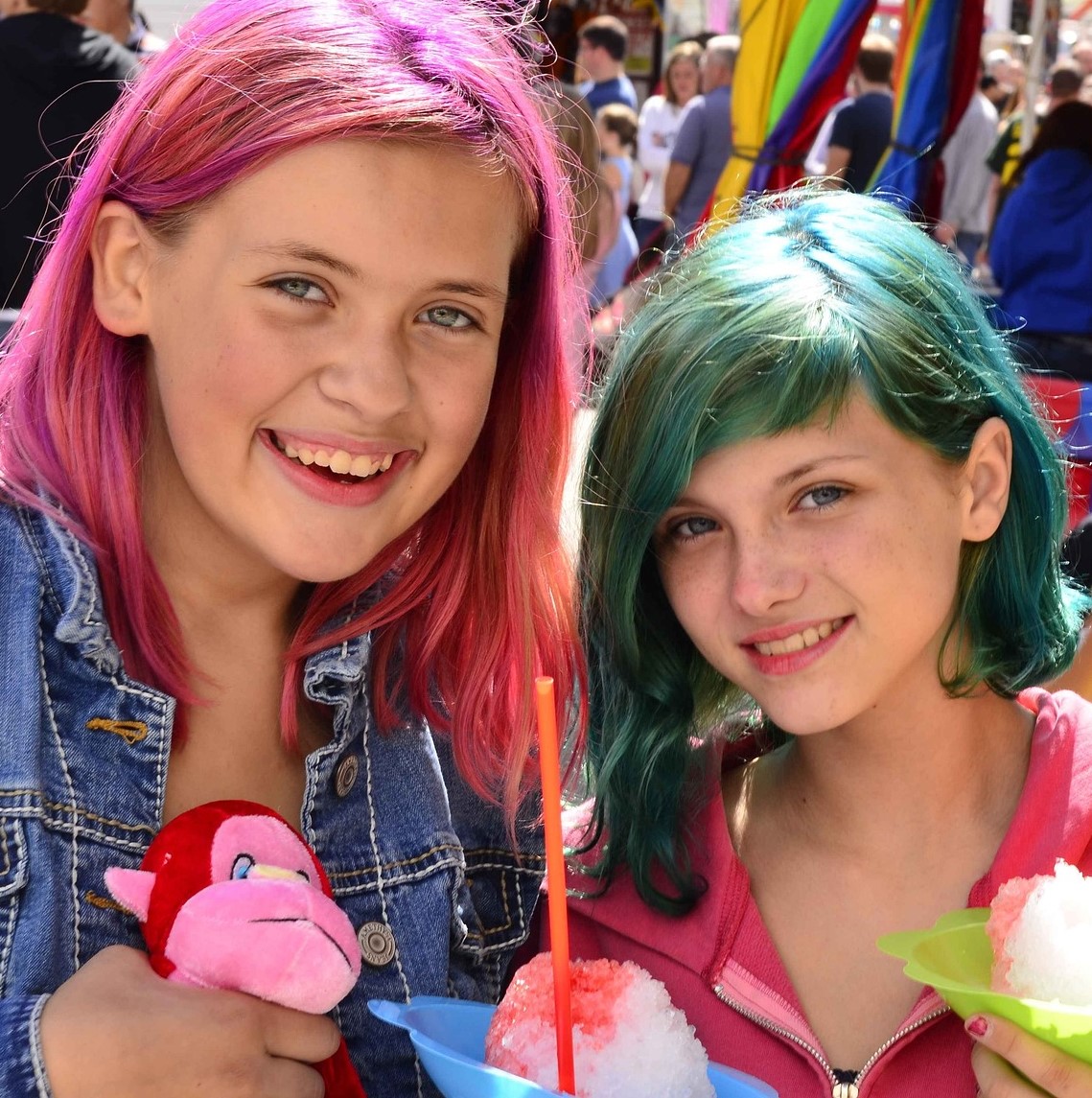 Kleurige foto van twee lachende tienermeisjes met roze en groen haar