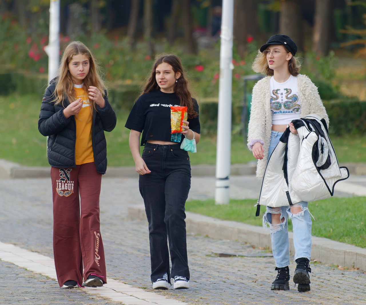 Drie buiten wandelende tienermeisjes in hippe vrijetijdskleding