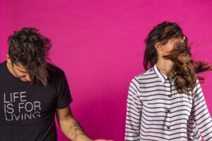 Tienerjongen en meisje die een dansbeweging maken tegen knalroze achtergrond