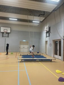 Foto van jongen met beperking die in een sportzaal onder begeleiding aan het sporten is - aan de ringen gant