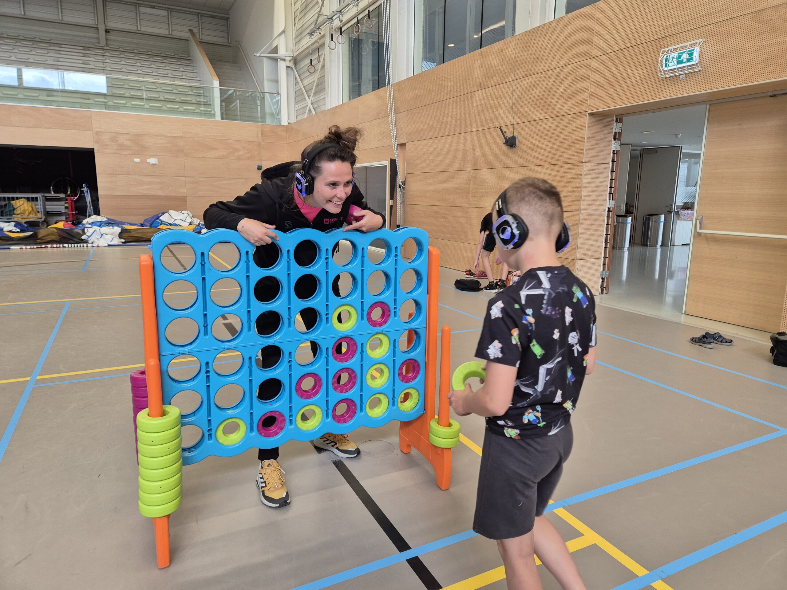 Foto van sportbegeleider en kind in een sportzaal die bezig zijn met een kleurrijk sportattribuut geschikt voor kinderen met een indicatie