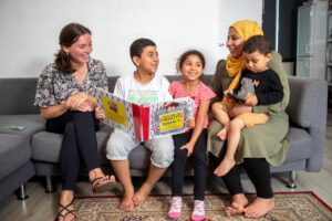 Foto van gezin en voorleesvrijwilliger die de kinderen voorleest